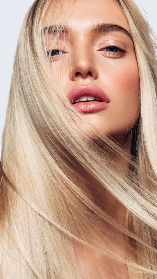 Close-up of a person with long blonde hair against a light background