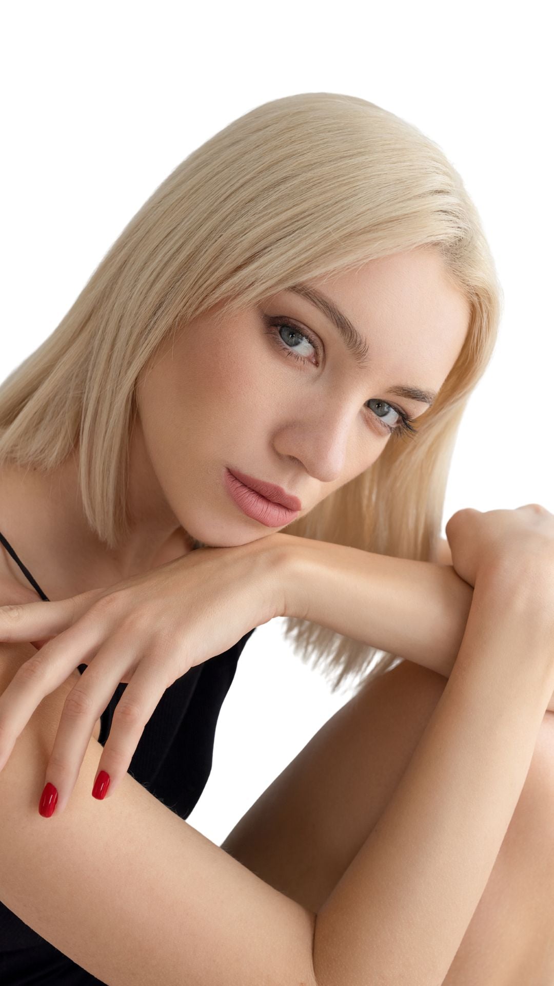 Woman with blonde hair and red nails posing against a white background