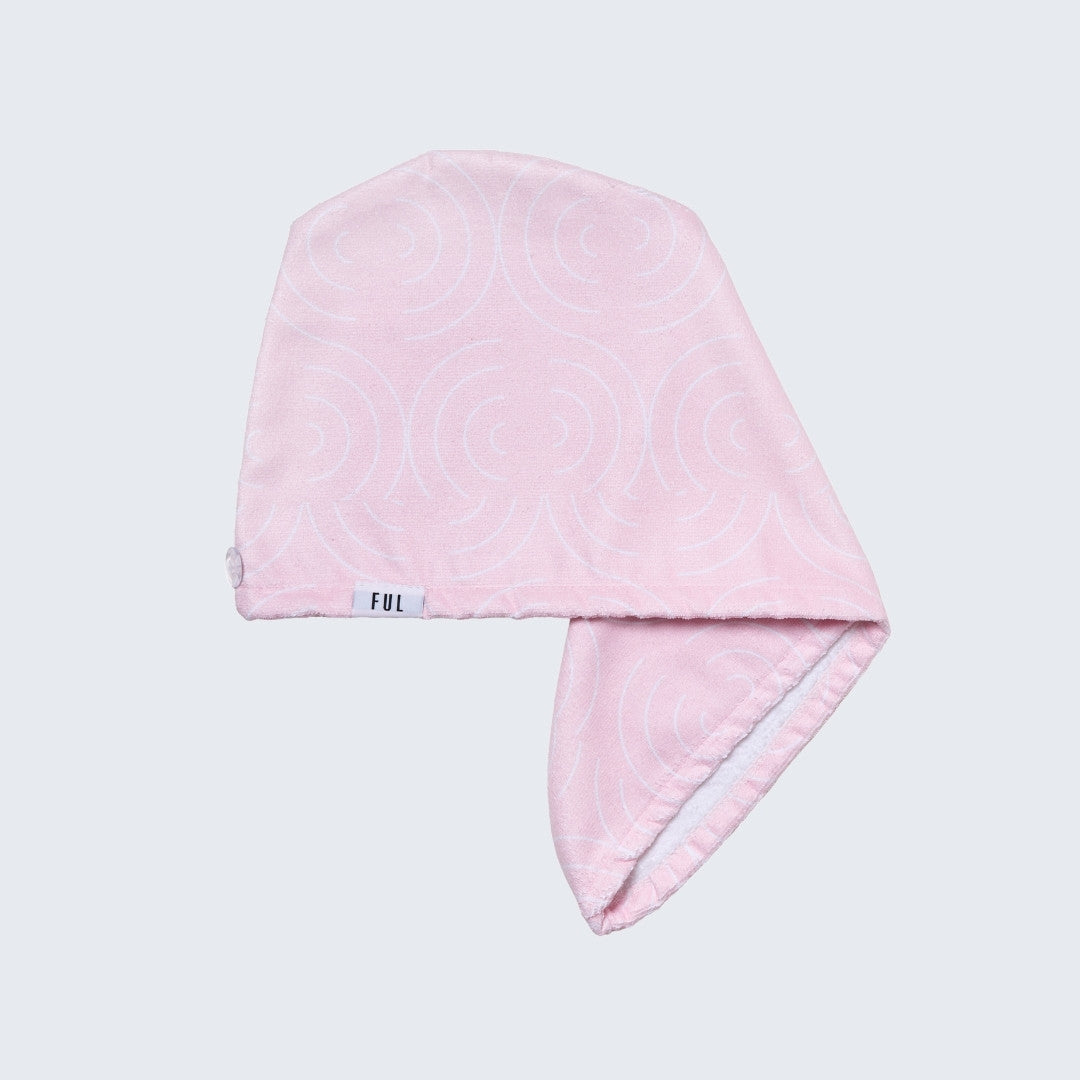 Pink towel with a brand label on a light gray background