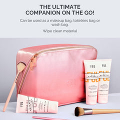 Pink toiletry bag with cosmetic products and brushes on a light gray background